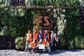 Squadra di tecnici davanti a una grande parete verde realizzata al Museo Ferroviario di Pietrarsa