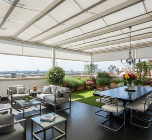 Vista di un terrazzo ampio con divani, tavolo da pranzo e angolo verde